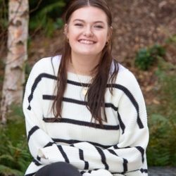 A woman with long hair wearing a striped sweater smiling