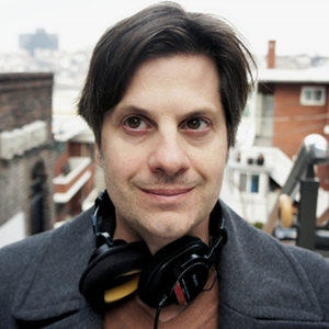 Man with brown hair wearing headphones around his neck