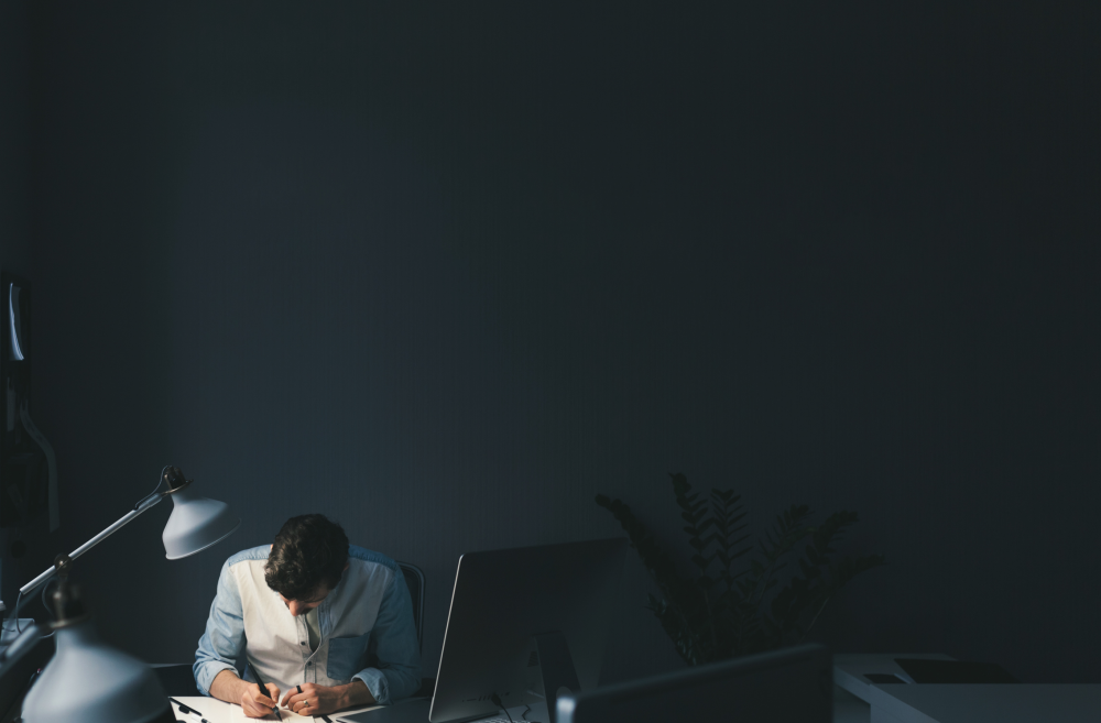 A journalist working along at a desk in a dark room